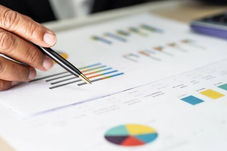 Asian accountant working and analyzing financial reports project accounting with chart graph and...