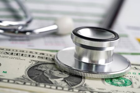 Stethoscope and US dollar banknotes on chart or graph paper, Financial, account, statistics and business data  medical health concept.の写真素材