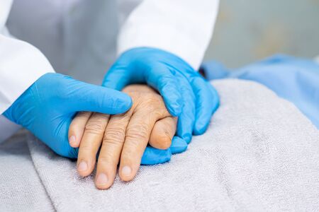 Doctor holding touching hands Asian senior or elderly old lady woman patient with love, care, helping, encourage and empathy at nursing hospital ward : healthy strong medical conceptの写真素材