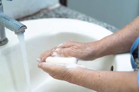Asian senior or elderly old lady woman patient washing hand by soap and clean water for protect infection and kill Novel Coronavirus (2019-nCoV) Covid-19 virus, bacteria and germs.の写真素材