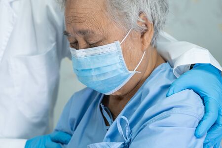 Doctor help Asian senior or elderly old lady woman patient wearing a face mask in hospital for protect safety infection and kill Novel Coronavirus (2019-nCoV) Covid-19 virus.の写真素材