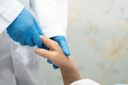 Doctor holding touching hands Asian senior or elderly old lady woman patient with love, care, helping, encourage and empathy at nursing hospital ward : healthy strong medical conceptの写真素材