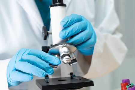 Asian scientist biochemist or microbiologist working research with a microscope in laboratory. For...