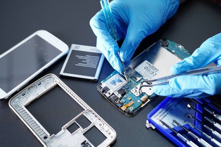 Asian Technician repairing micro circuit main board of smartphone electronic technology : computer,...