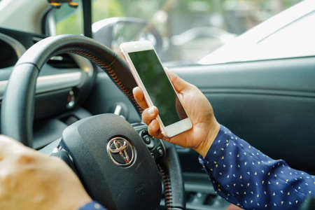 Bangkok, Thailand - February 25, 2019: Holding iPhone in toyota sienta car to communication with family and friends.のeditorial素材