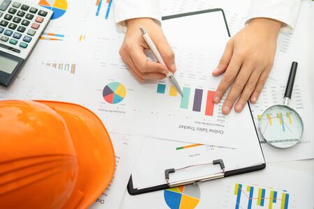 Asian accountant working and analyzing financial reports project accounting with chart graph and...