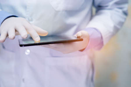 Asian senior or elderly old lady woman patient holding in her hands digital tablet and reading emails while sitting on bed in nursing hospital ward, healthy strong medical conceptの写真素材