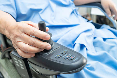Asian senior or elderly old lady woman patient on electric wheelchair with remote control at nursing...