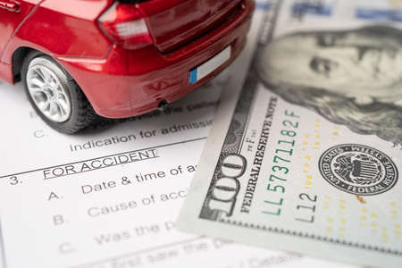 Health insurance accident claim form with US dollar banknotes money and car.の写真素材