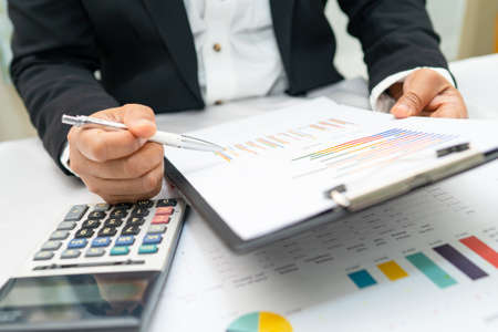 Asian accountant working and analyzing financial reports project accounting with chart graph and...