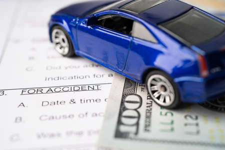 Health insurance accident claim form with US dollar banknotes money and car.の写真素材