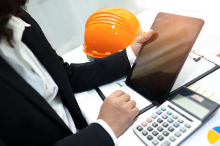 Architect or engineer working project accounting with graph and construction helmet in office,...