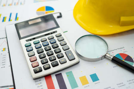 Calculator on graph with construction helmet for working project in office.の写真素材