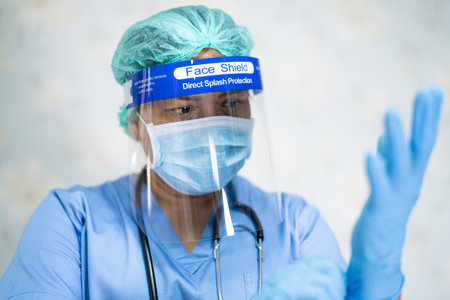 Asian doctor wearing face shield and PPE suit new normal to check patient protect safety infection Covid-19 Coronavirus outbreak at quarantine nursing hospital ward.の写真素材