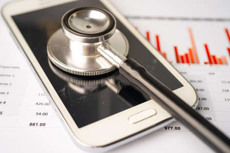 Stethoscope with mobile phone on graph paper, Finance, Account, Statistics, Investment, Analytic research data economy business and technology company concept.の写真素材