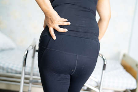 Asian lady patient wearing back pain support belt for orthopedic lumbar with walker.の写真素材