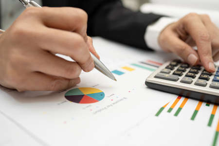 Asian accountant working and analyzing financial reports project accounting with chart graph and...