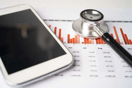 Stethoscope with mobile phone on graph paper, Finance, Account, Statistics, Investment, Analytic research data economy business and technology company concept.の写真素材