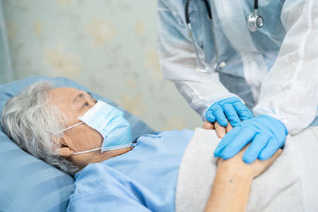 Doctor using stethoscope to checking Asian senior or elderly old lady woman patient wearing a face mask in hospital for protect infection Covid-19 Coronavirus.の写真素材