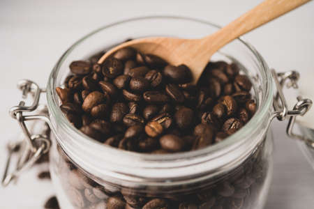 Coffee bean in glass jar bottle with wooden spoon in fresh drink food morning.の写真素材