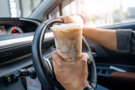 Asian lady holding ice coffee for drink food in car dangerous and risk an accident.の写真素材