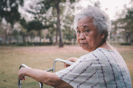 Asian senior or elderly old lady woman patient walk with walker in park with copy space, healthy strong medical conceptの写真素材