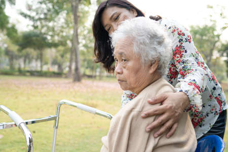 Help and care Asian senior or elderly old lady woman use walker with strong health while walking at park in happy fresh holiday.の写真素材