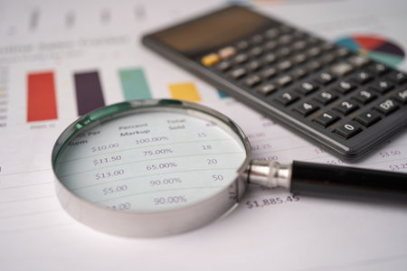 Magnifying glass and calculator on charts graphs paper. Financial development, Banking Account,...