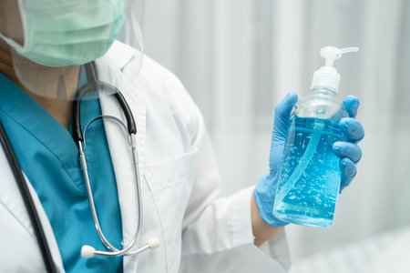 Doctor holding blue alcohol sanitizer gel for patient to protect safety infection and kill Novel Coronavirus Covid-19 virus, bacteria and germs.の写真素材