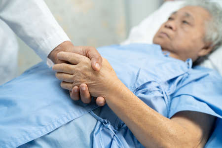 Doctor holding hands Asian senior or elderly old lady woman patient with love, care, encourage and empathy at nursing hospital ward, healthy strong medical conceptの写真素材