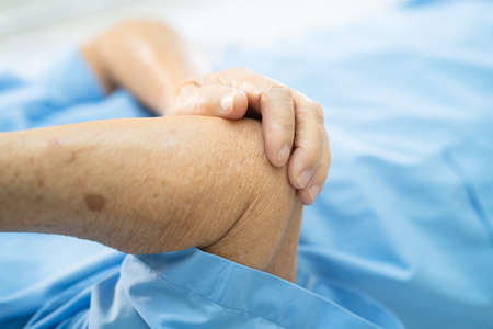 Asian senior or elderly old lady woman patient feel pain her elbow on bed in nursing hospital ward,...