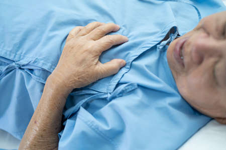Asian senior or elderly old lady woman patient feel pain in the chest and heart on bed in nursing hospital ward; healthy strong medical concept.の写真素材