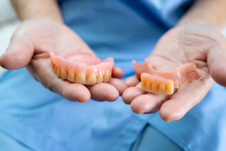 Asian senior or elderly old woman patient holding to use denture in nursing hospital ward, healthy strong medical conceptの写真素材