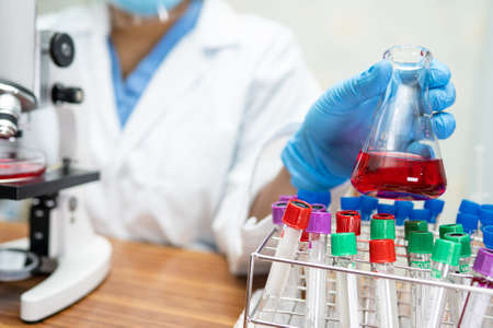 Asian scientist research with a microscope in laboratory.