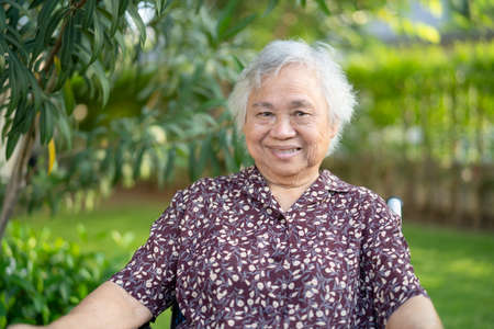 Asian senior or elderly old lady woman patient smile on wheelchair in park, healthy strong medical conceptの写真素材