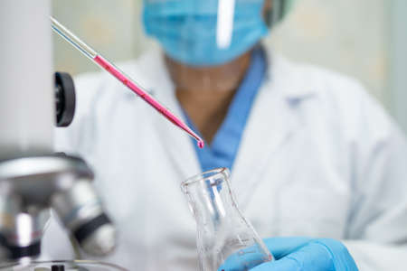 Asian scientist biochemist or microbiologist working research with a microscope in laboratory. For protect outbreakの写真素材
