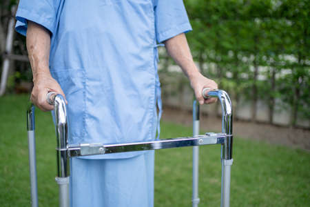 Asian senior or elderly old lady woman use walker with strong health while walking at park in happy fresh holiday.の写真素材