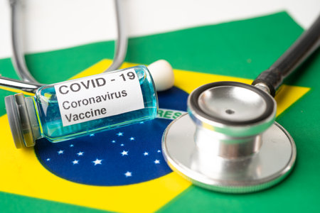 Stethoscope with Covid-19 Coronavirus vaccine on Brazil flag.の写真素材