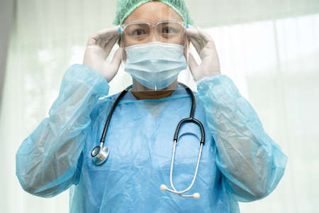 Asian doctor wearing face shield and PPE suit new normal to check patient protect safety infection...