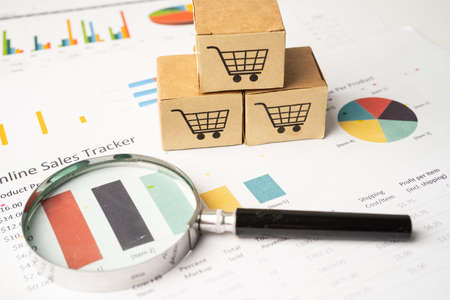 Shopping cart  on box with magnifying glass on graph background. Banking Account, Investment...