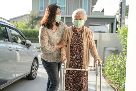 Asian senior or elderly old lady woman walk with walker and wearing a face mask for protect safety...