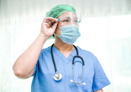 Asian doctor wearing mask, face shield and PPE suit new normal isolated on white background with clipping path to protect safety infection Covid-19 Coronavirus.の写真素材