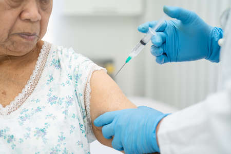 Elderly Asian senior woman wearing face mask getting  vaccine by doctor make injection.の写真素材