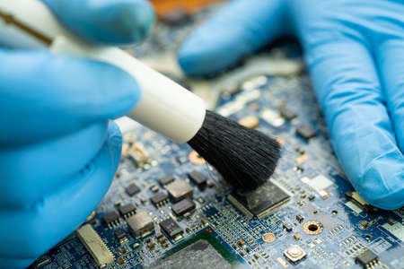 Technician use brush and air blower ball to clean dust in circuit board computer. Repair upgrade and maintenance technology.の写真素材