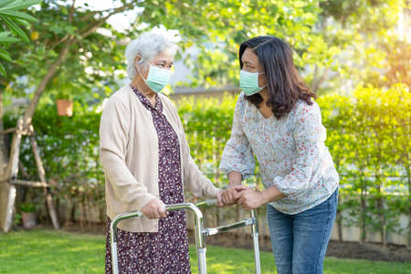 Asian senior or elderly old lady woman walk with walker and wearing a face mask for protect safety...