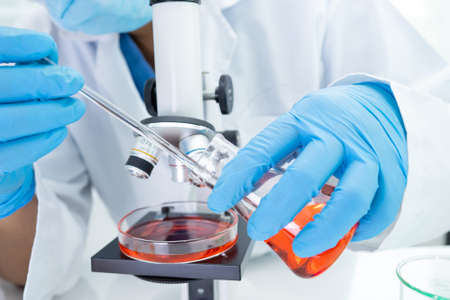 Asian scientist biochemist or microbiologist working research with a microscope in laboratory. For...