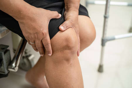Asian middle-aged lady woman patient touch and feel pain her knee, healthy medical concept.の写真素材