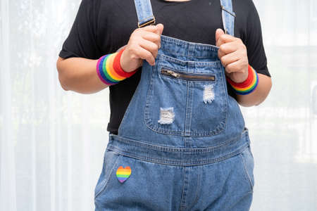 Asian lady wearing rainbow flag wristbands, symbol of LGBT pride month celebrate annual in June...