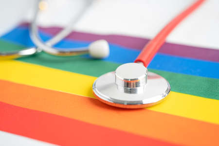 Red stethoscope on rainbow flag background, symbol of LGBT pride month celebrate annual in June social, symbol of gay, lesbian, bisexual, transgender, human rights and peace.の写真素材