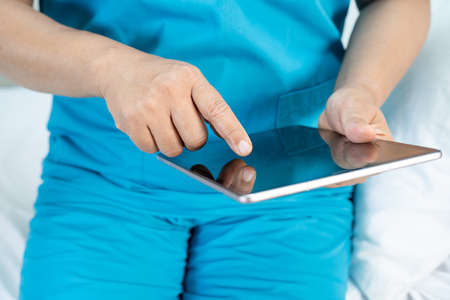Doctor holding digital tablet to search data for treat patient in nursing hospital ward : healthy strong medical concept.の写真素材